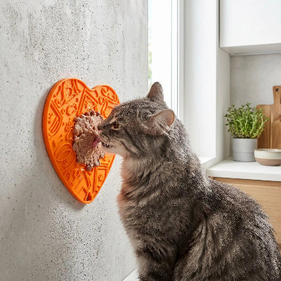 Chat gris qui lèche son Tapis de léchage-pour chat coeur orange fixe sur mur